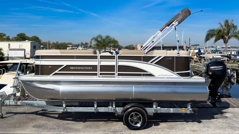Slide: The Image of 2024 Bennington 188 SL pontoon boat on trailer, featuring Mercury outboard motor. - 1