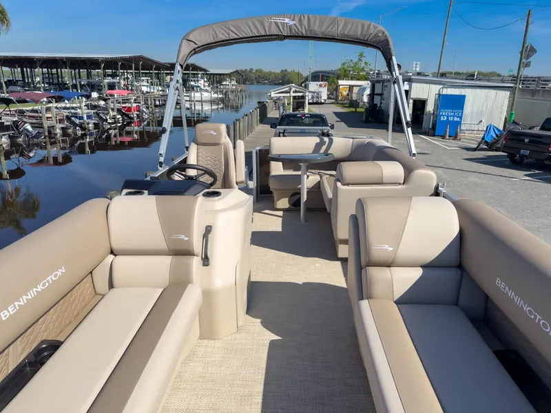 Slide: The Image of 2024 Bennington 188 SL pontoon boat with beige seating, docked near a marina. - 11