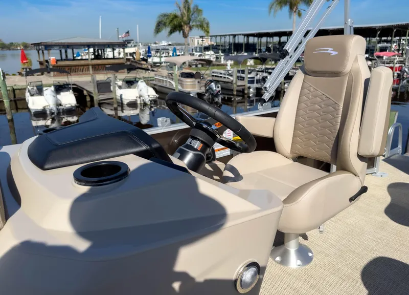 Slide: The Image of 2024 Bennington 188 SL boat helm with beige captain's chair and steering wheel at marina. - 23