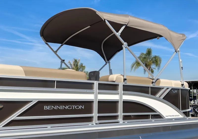 Slide: The Image of 2024 Bennington 188 SL pontoon boat with canopy, set against a clear blue sky. - 32