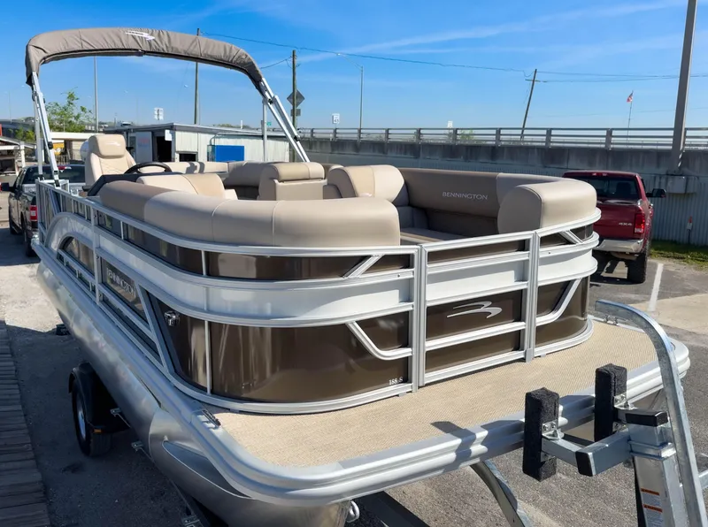 Slide: The Image of 2024 Bennington 188 SL pontoon boat on trailer, featuring beige seating and sleek design. - 5
