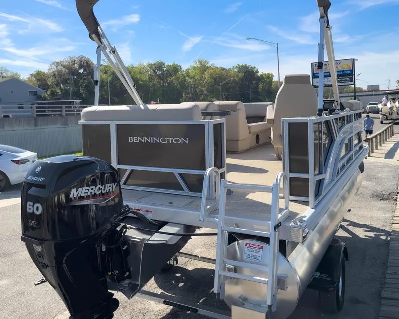 Slide: The Image of 2024 Bennington 188 SL pontoon boat with Mercury 60 HP engine, parked outdoors. - 6