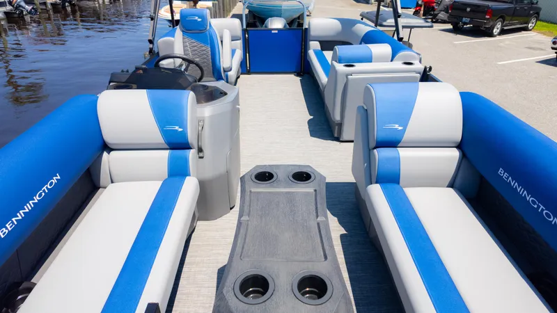 Slide: The Image of 2024 Bennington 20 SSR pontoon boat interior with blue and gray seating, docked by the water. - 10
