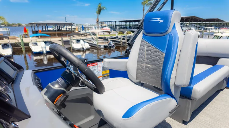 Slide: The Image of 2024 Bennington 20 SSR boat interior with blue and gray seating at a marina. - 27