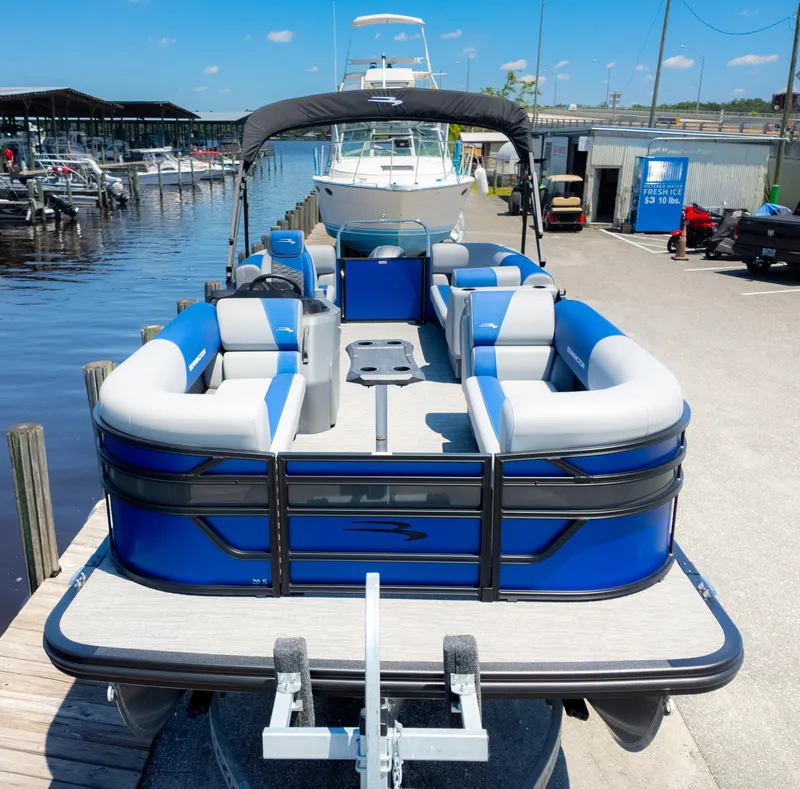 Slide: The Image of 2024 Bennington 20 SSR pontoon boat docked, featuring blue and gray seating, under a clear sky. - 3