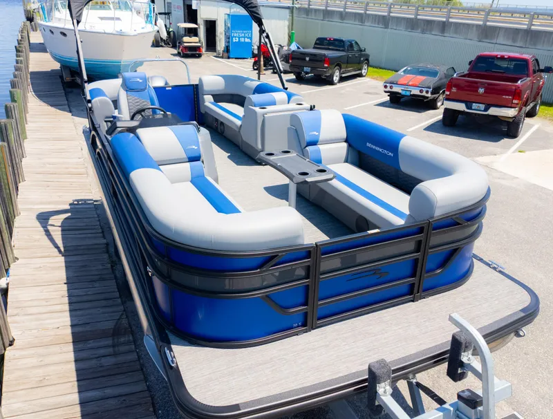 Slide: The Image of 2024 Bennington 20 SSR pontoon boat docked, featuring blue and gray seating. - 4