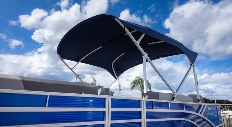Slide: The Image of 2025 Bennington 20 SVS Stern Fish pontoon boat with blue canopy under cloudy sky. - 3