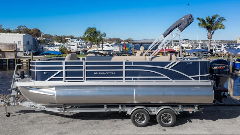 Slide: The Image of 2025 Bennington 21 SF pontoon boat on trailer at marina. - 1