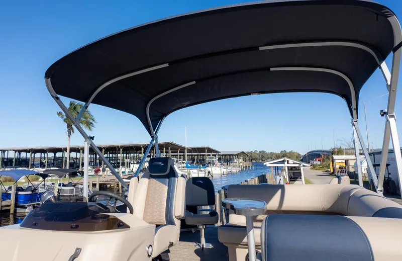 Slide: The Image of 2025 Bennington 21 SF pontoon boat with canopy at marina, clear blue sky. - 28