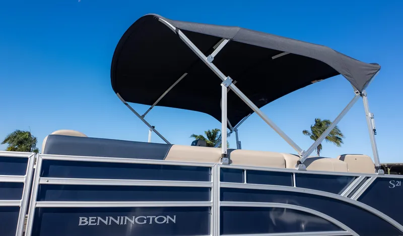 Slide: The Image of 2025 Bennington 21 SF pontoon boat with canopy against clear blue sky. - 29