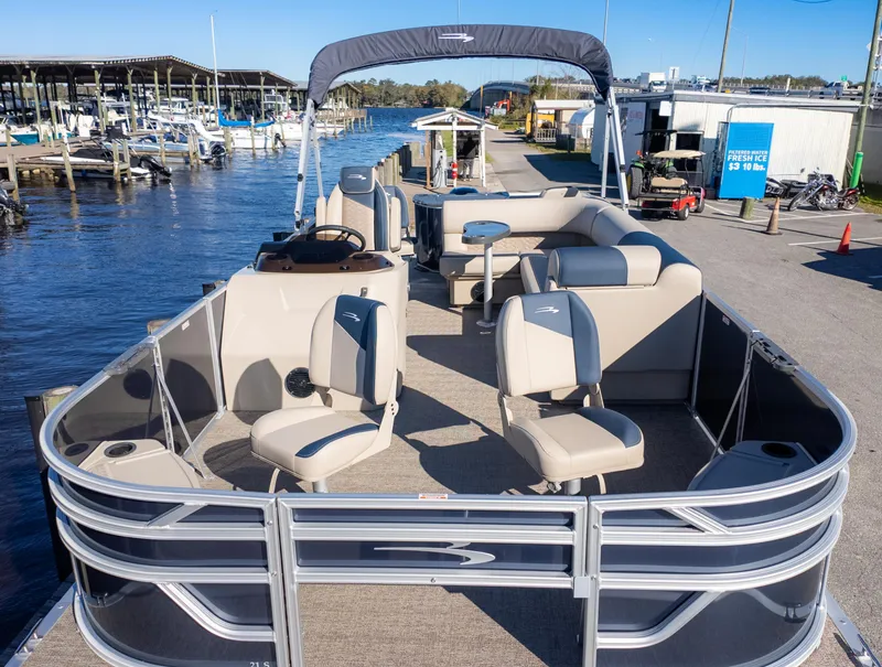 Slide: The Image of 2025 Bennington 21 SF pontoon boat docked at a marina, featuring spacious seating and modern design. - 3
