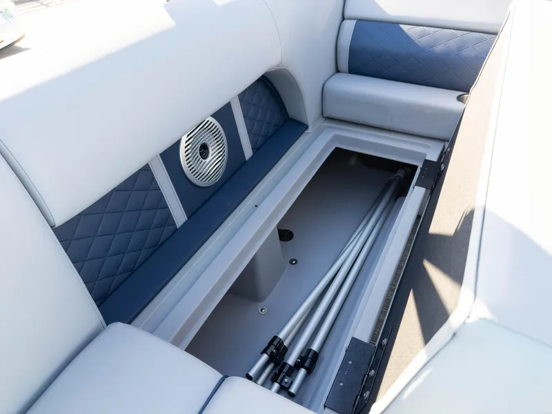 Slide: The Image of 2024 Bennington 22 LSB boat interior storage compartment with speaker and cushioned seating. - 22