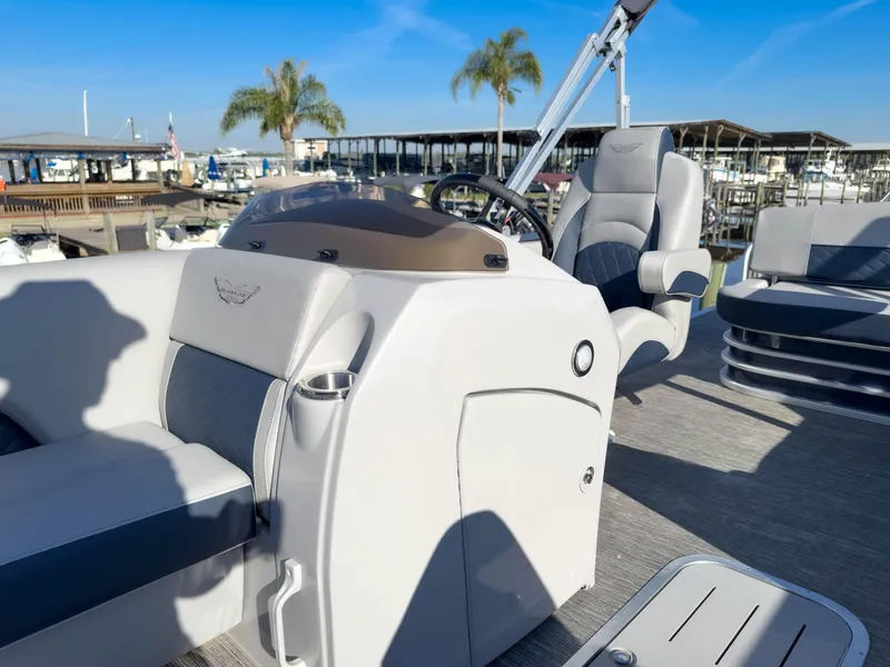 Slide: The Image of 2024 Bennington 22 LSB boat interior with helm, seating, and marina background. - 32