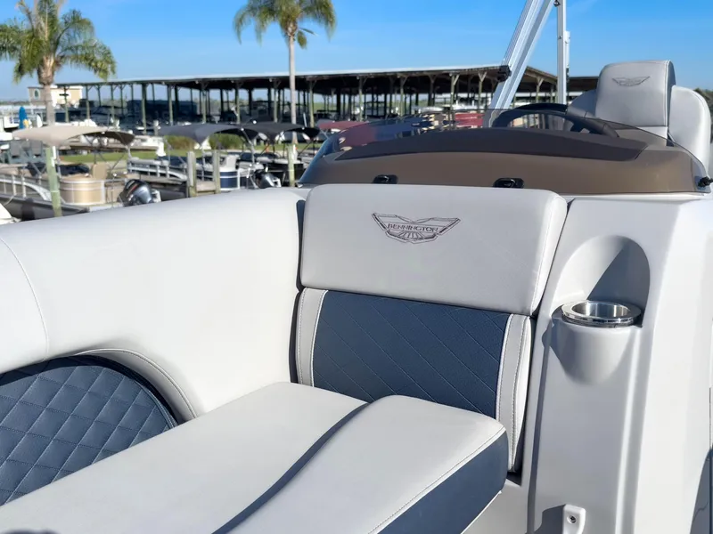 Slide: The Image of 2024 Bennington 22 LSB boat interior with luxurious seating and cup holder, docked near palm trees. - 40