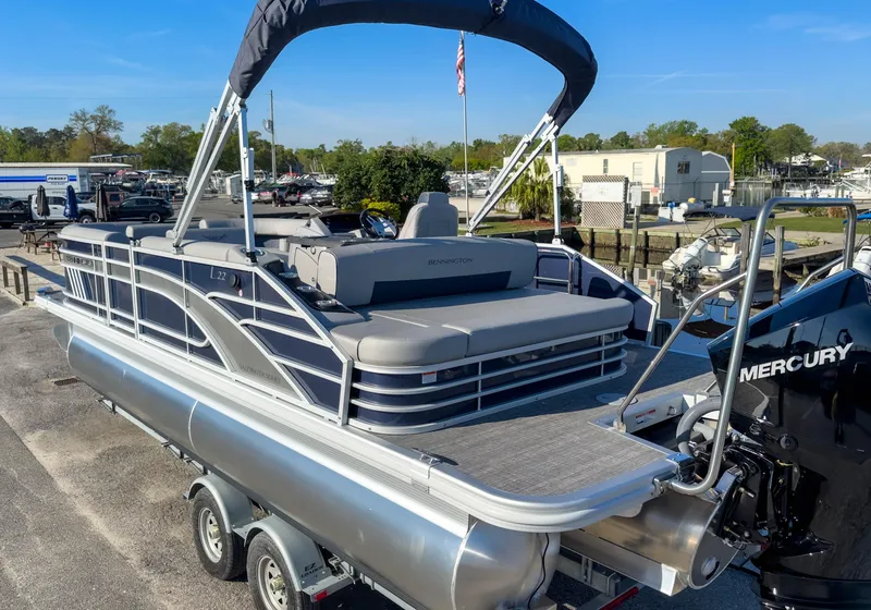 Slide: The Image of 2024 Bennington 22 LSB pontoon boat with Mercury engine, docked on a trailer. - 8