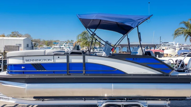 Slide: The Image of 2025 Bennington 22 MSB pontoon boat with blue canopy, docked in marina. - 1