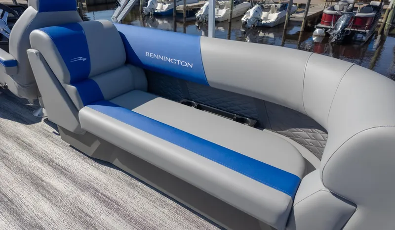 Slide: The Image of 2025 Bennington 22 SSR boat interior with blue and gray seating at a marina. - 10