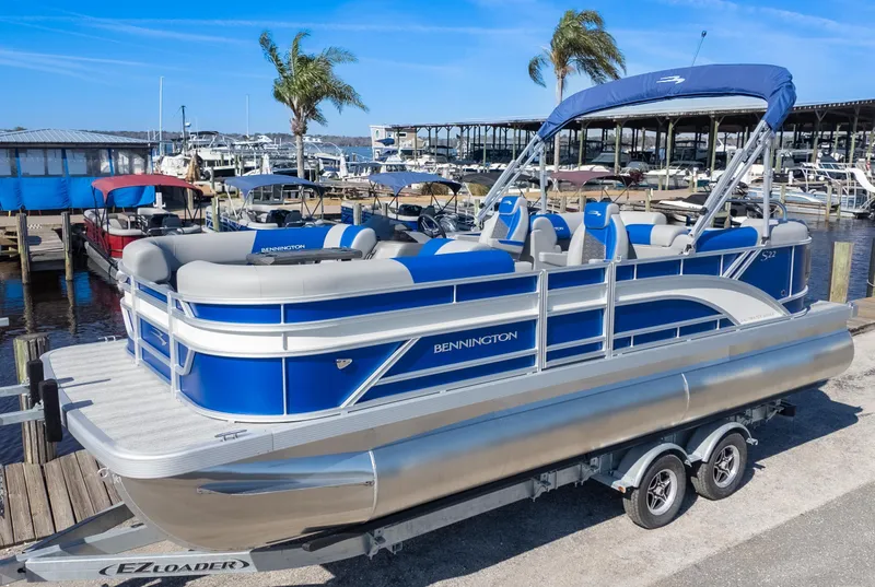 Slide: The Image of 2025 Bennington 22 SSR pontoon boat docked at a marina with blue accents. - 2