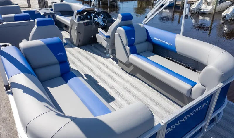 Slide: The Image of 2025 Bennington 22 SSR pontoon boat with blue and gray seating, docked by the water. - 6