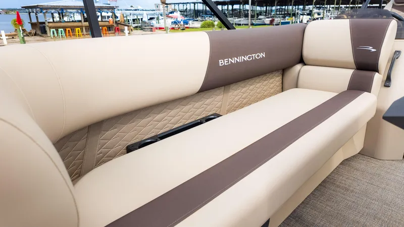 Slide: The Image of 2025 Bennington 22 SSR boat interior with beige and brown seating, dockside view. - 19