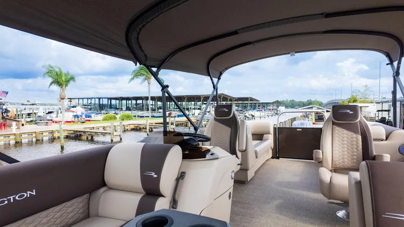 Slide: The Image of 2025 Bennington 22 SSR pontoon boat interior with luxurious seating and canopy at a marina. - 29