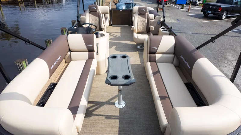 Slide: The Image of 2025 Bennington 22 SSR pontoon boat interior with plush seating and table, docked by water. - 3