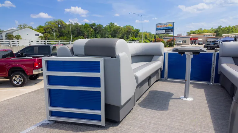 Slide: The Image of 2024 Bennington 22 SVSB pontoon boat interior with seating and table, parked outdoors. - 20