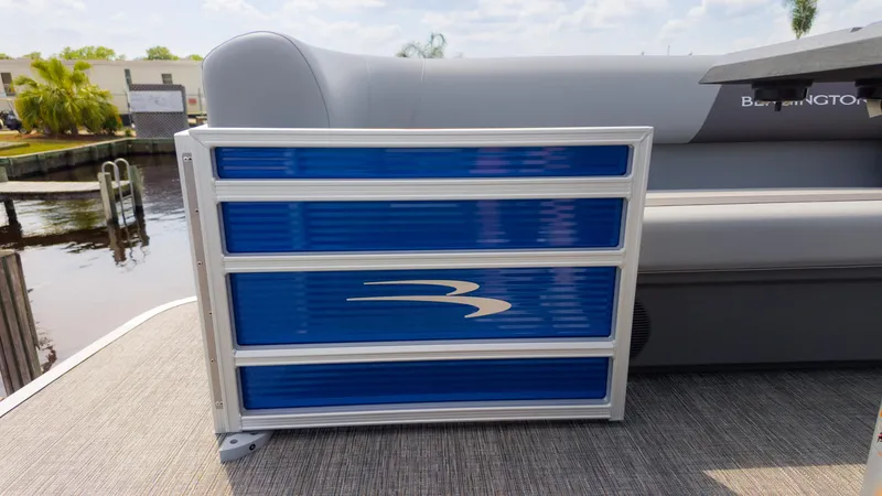 Slide: The Image of 2024 Bennington 22 SVSB pontoon boat with blue paneling, docked by a canal. - 23