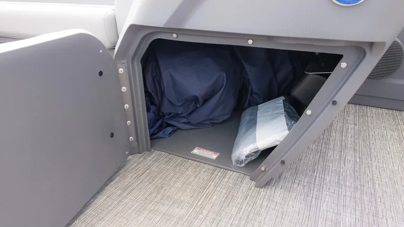 Slide: The Image of 2024 Bennington 22 SVSB storage compartment with fabric and packaged items inside. - 26