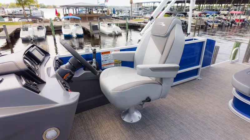 Slide: The Image of 2024 Bennington 22 SVSB boat interior with captain's chair and steering wheel at marina. - 27