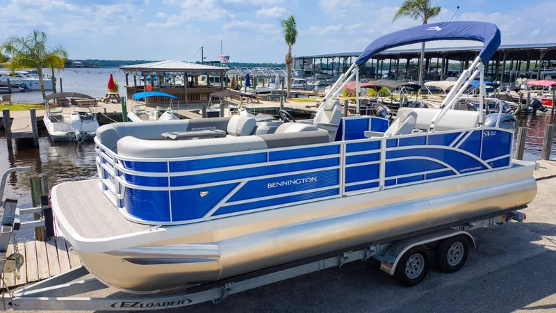 Slide: The Image of 2024 Bennington 22 SVSB pontoon boat docked at a marina with blue accents. - 3