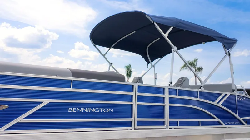Slide: The Image of 2024 Bennington 22 SVSB pontoon boat with blue exterior and canopy under a clear sky. - 31