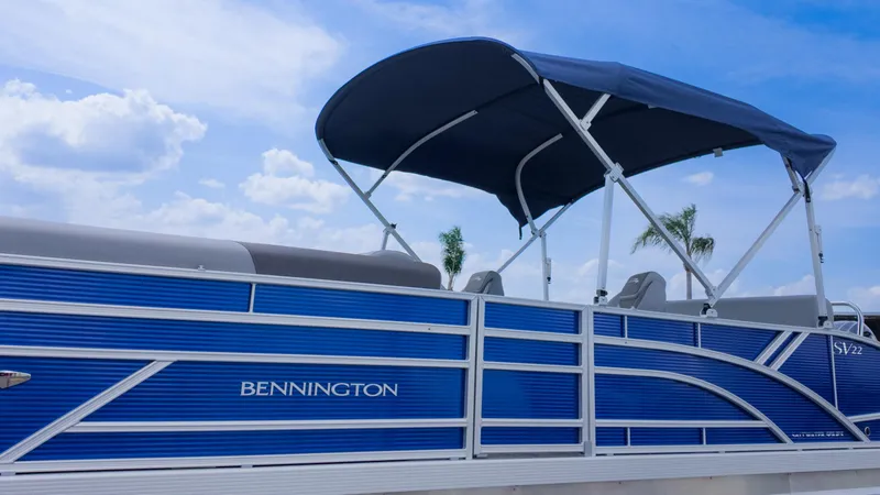 Slide: The Image of 2024 Bennington 22 SVSB pontoon boat with blue exterior and canopy under a clear sky. - 32