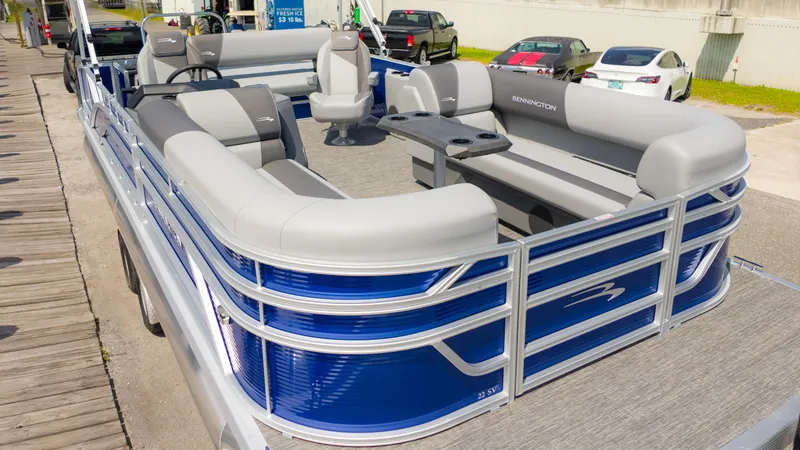 Slide: The Image of 2024 Bennington 22 SVSB pontoon boat with sleek blue and gray design, docked outdoors. - 4