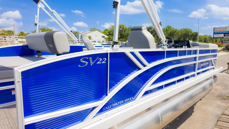 Slide: The Image of 2024 Bennington 22 SVSB pontoon boat in vibrant blue, docked under a clear sky. - 5