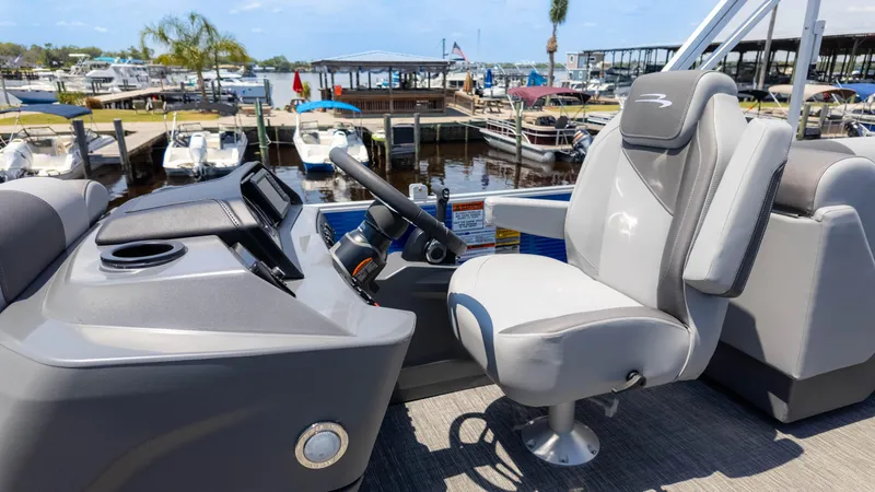 Slide: The Image of 2024 Bennington 22 SVSR boat interior with helm and captain's chair at marina. - 22