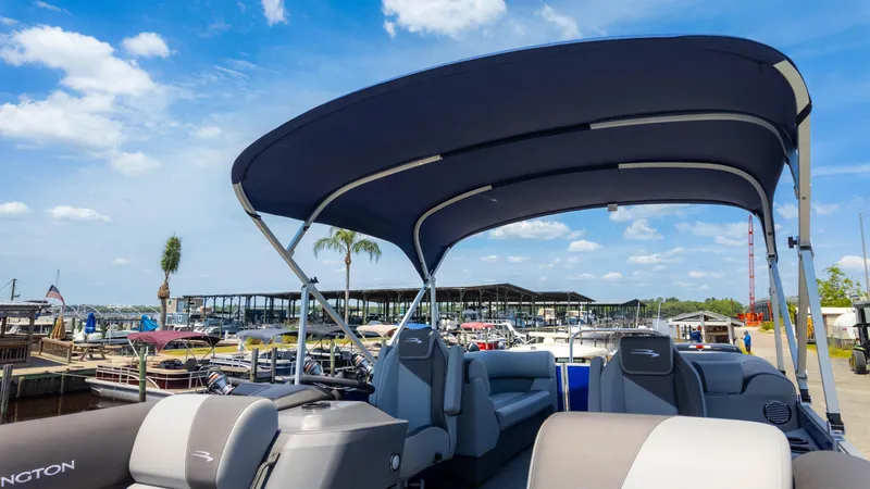 Slide: The Image of 2024 Bennington 22 SVSR pontoon boat with canopy at marina under blue sky. - 24