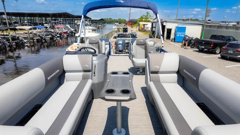 Slide: The Image of 2024 Bennington 22 SVSR pontoon boat interior at marina, featuring spacious seating and table. - 8