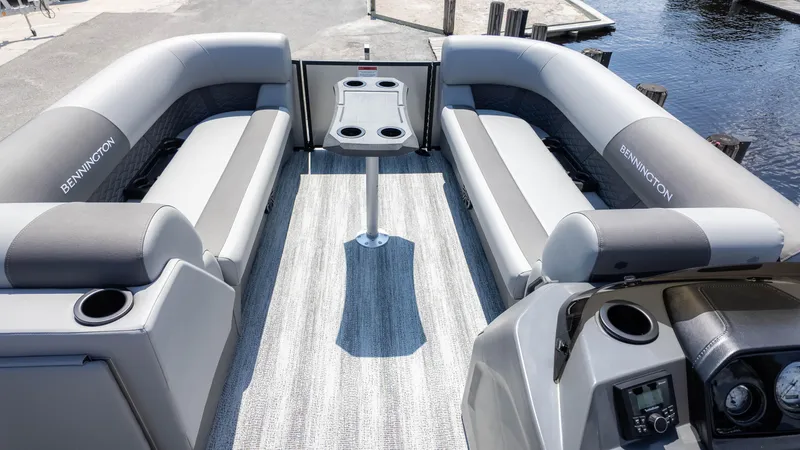 Slide: The Image of 2025 Bennington 23 SSB pontoon boat interior with gray seating and table, docked by water. - 10