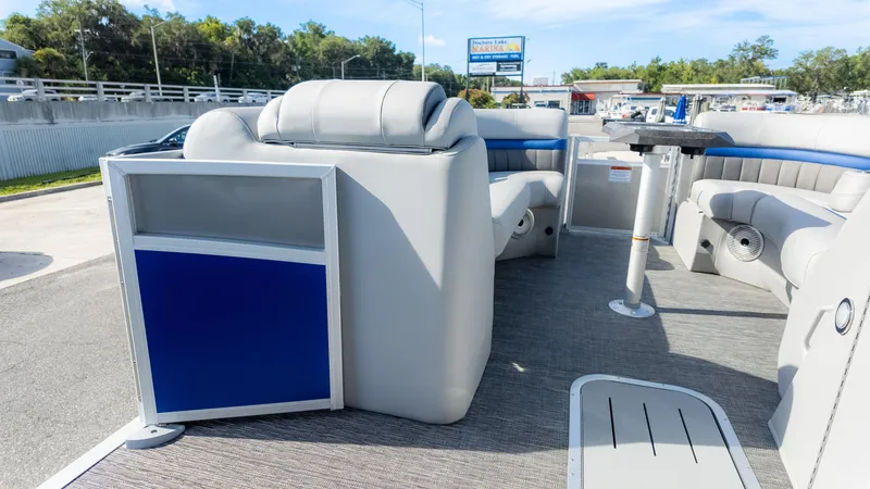 Slide: The Image of 2024 Bennington 24 LXSFBA pontoon boat interior with seating and table, docked at marina. - 19