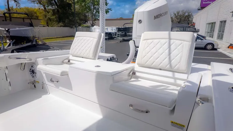 Slide: The Image of 2025 Everglades 253CC boat with white cushioned seats and Mercury engine in a parking lot. - 12