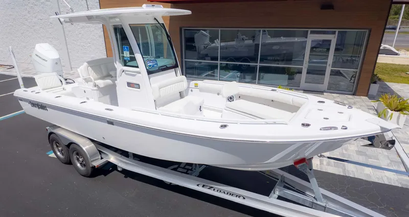 Slide: The Image of 2025 Everglades 253CC boat on trailer, parked outside a showroom. - 2