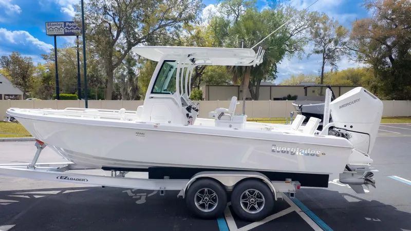 Slide: The Image of 2025 Everglades 253CC boat on trailer, parked outdoors under a clear sky. - 4