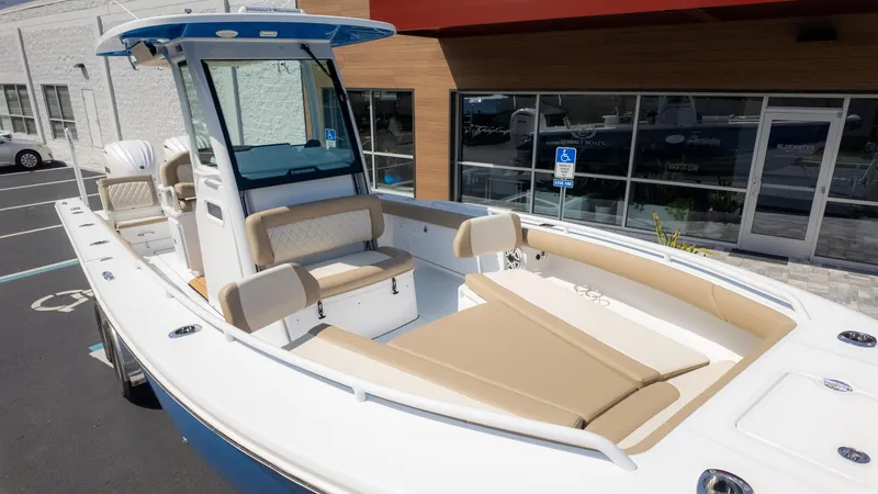 Slide: The Image of 2025 Everglades 273CC boat with beige seating, docked near a modern building. - 12