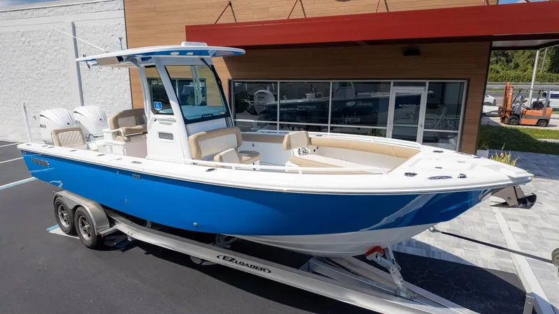 Slide: The Image of 2025 Everglades 273CC boat in blue on trailer, parked outside a showroom. - 3
