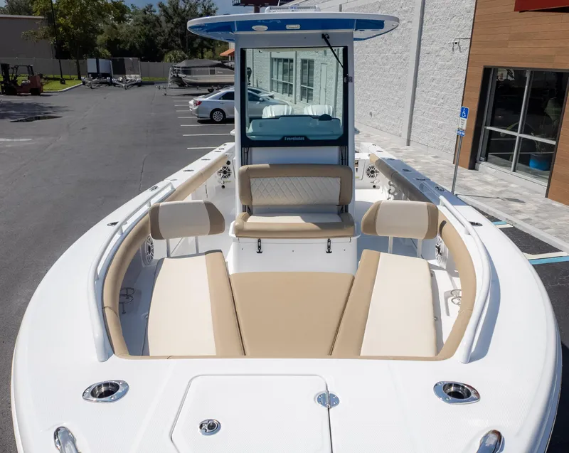 Slide: The Image of 2025 Everglades 273CC boat with beige seating, docked in a parking area. - 5