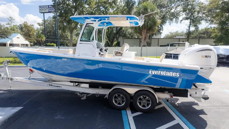 Slide: The Image of 2025 Everglades 273CC boat on trailer, vibrant blue hull, parked outdoors. - 7