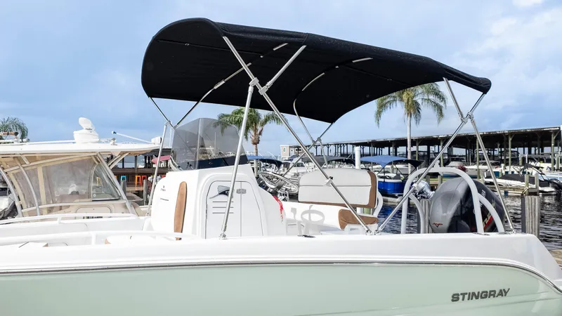 Slide: The Image of 2025 Stingray 173CC boat with canopy, docked at marina under cloudy sky. - 18