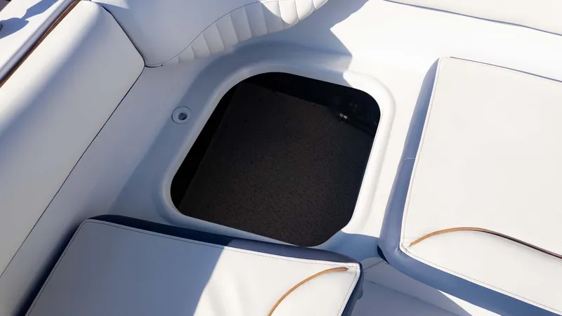 Slide: The Image of 2025 Stingray 192SC boat interior storage compartment with white cushioned seating. - 15