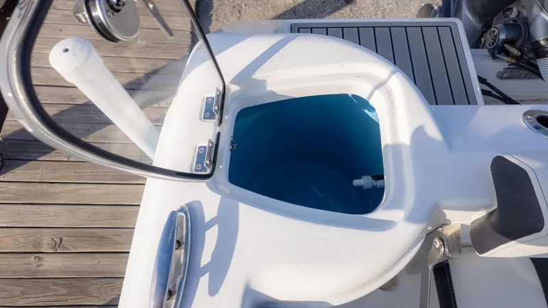 Slide: The Image of 2025 Tidewater 220cc boat livewell with open lid, dockside view. - 10